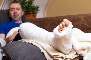 Mann liegt mit einem gebrochenen Fuß zuhause auf dem Sofa
